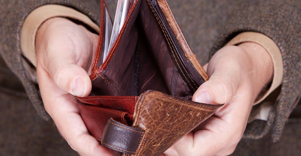 Man in a suit holding an empty wallet in two hands