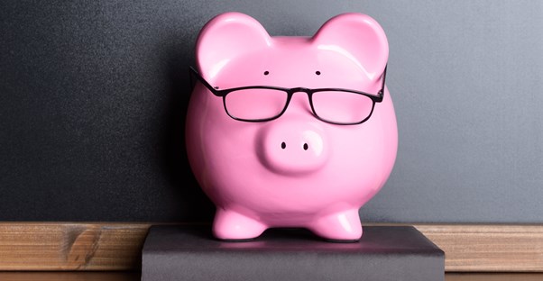 Nerdy piggy bank sitting on a book on a shelf