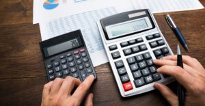 A business owner doing math to calculate the fees of a high risk merchant account