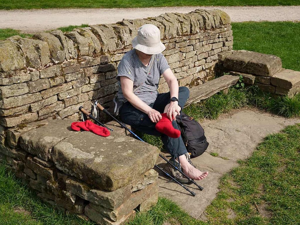 A woman attends to her feet during a walk through the Derbyshire Dales in Bakewell, England.