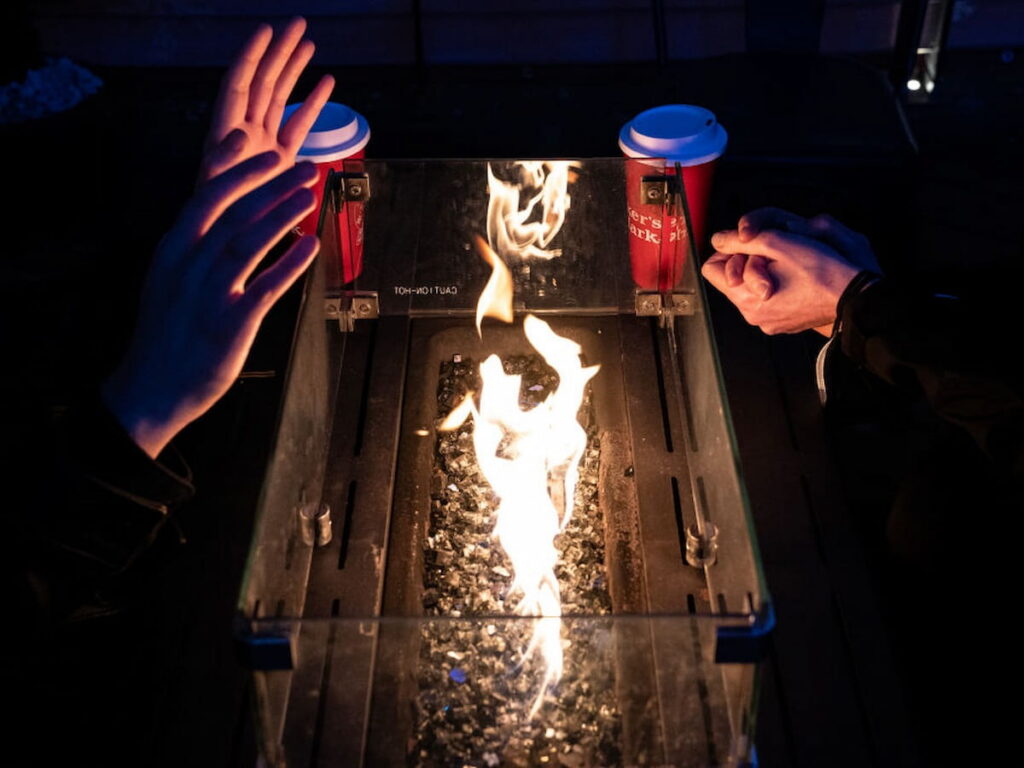 Patrons warm their hands over a gas-powered fire pit while meeting for a drink in Washington, DC.